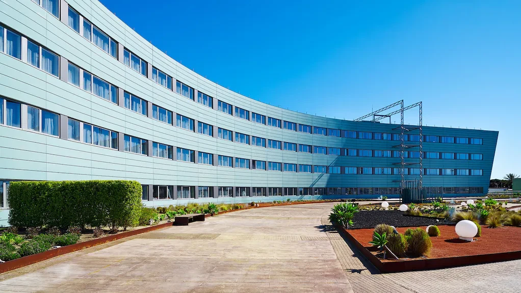 Fachada curva del Barcelona Airport Hotel con el jardín y el paseo de la entrada